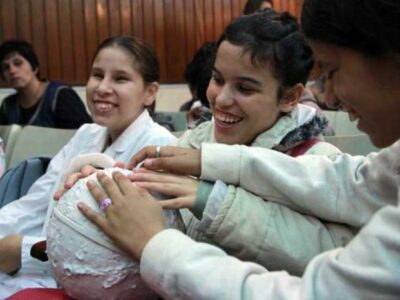 Astronomy for Equity. Two smiling children who have blindness learn astronomy by feeling dots and texture on globes the size of a basketball.